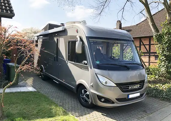 Ein Wohnmobil der Marke Hymer steht in einer Einfahrt.