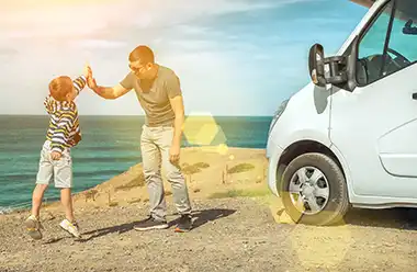 Foto eines Vater mit seinem Sohn am Strand mit einem Wohnmobil.